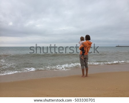 Back view of mother with child on beach dark cloud sky outdoors background. Book cover idea design style