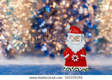Close-up Figurine toy Santa Claus on colorful golden and blue bokeh background. New Year or Christmas picture.