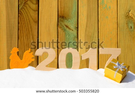 Christmas background with Rooster and the numbers 2017 in a snowdrift on a wooden background