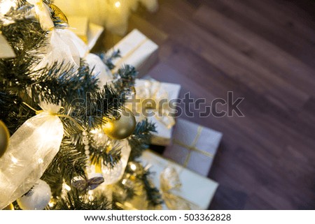 Tall christmas tree, beautifully decorated with balls, bows and lights. Lots of christmas gifts under the tree. Wooden food. Empty space, post card