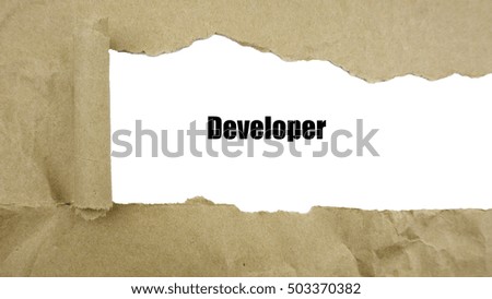 Torn brown paper on white surface with "developer" word.