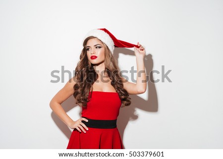 Beautiful young brunette woman in red dress and hat posing isolated over white background