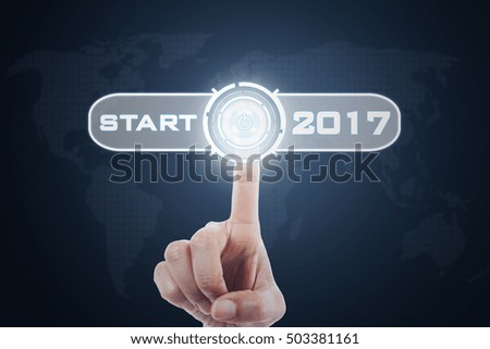 Image of hand pressing a virtual start button with numbers 2017 and world map background on the futuristic screen
