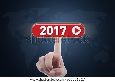 Picture of hand touching a virtual button with numbers 2017 and world map background on the futuristic screen