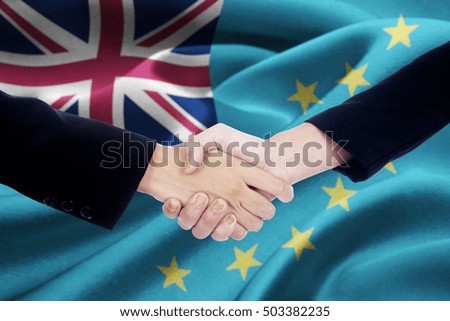 Image of Two business team shaking hands in front of Tuvalu flag waving in the wind