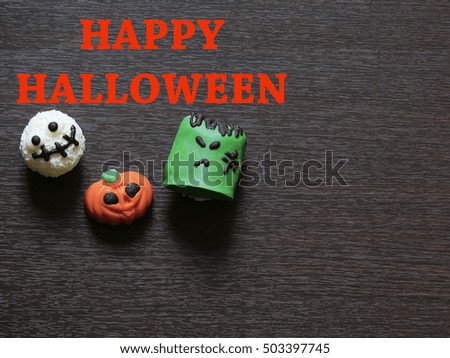 Variety chocolate monsters, jack-o'-lantern, green Frankenstein,white coconut ghost, for Halloween on brown wooden background with copyspace
