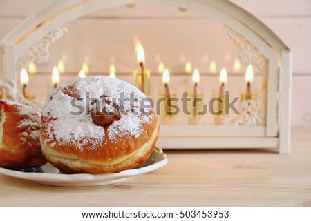 Selective focus image of jewish holiday Hanukkah with menorah (traditional Candelabra) and donuts