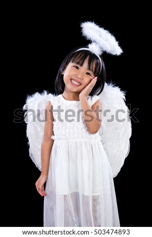 Smiling Asian Chinese Little Angel in dark black isolated studio background.