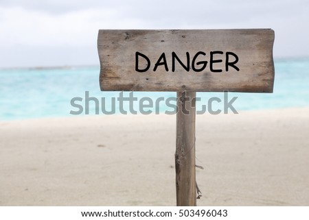 wooden sign with word danger on the beach