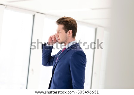 Side view of young businessman using mobile phone in new office