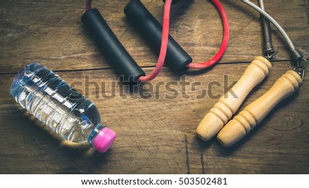 resistance band ,jump rope and water bottle on wooden block - vintage color style effect Royalty-Free Stock Photo #503502481