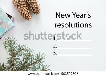 Lay flat view of Christmas decoration, cones, fir tree branch, gift box. Space for a text or design in the right. High angle. Text "New Year resolutions"