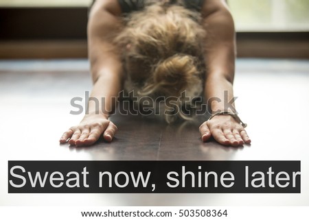 Attractive young woman working out at home, doing yoga exercise on blue mat, lying in Balasana, Child Pose. Close-up, focus on hands. Motivational text "Sweat now, shine later"