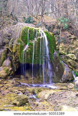 full-flowing waterfall in spring forest