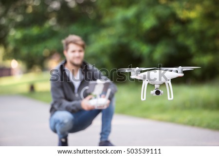 Young hipster man with flying drone. Sunny green nature. Royalty-Free Stock Photo #503539111