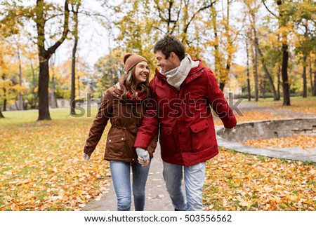 love, relationships, season and people concept - happy young couple walking in autumn park and talking