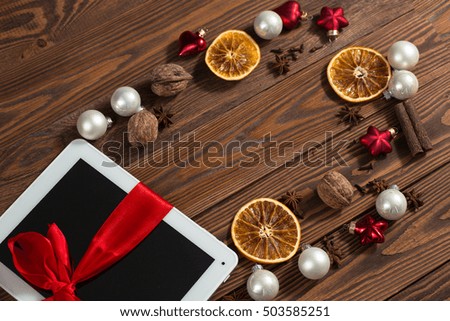 copyspace  tablet with  red ribbon bow and christmas tree toys  gift on wooden background, concept of New Year and Christmas
