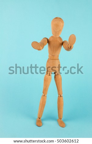 Wooden Mannequin Posing on Blue Background.