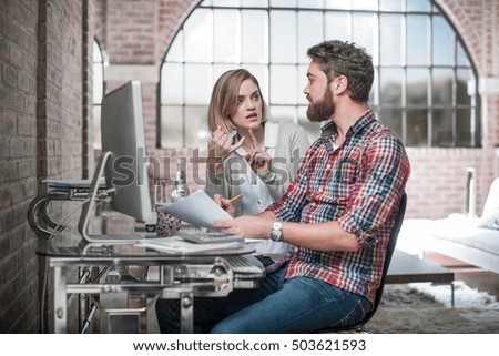 Couple at home, sitting at desk, using computer, having discussion, man holding paperwork