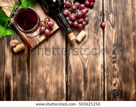 Red wine with a vine branch. On a wooden table.
