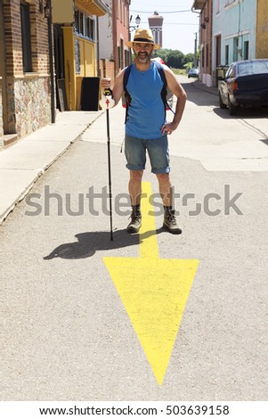 pilgrim wtih yellow arrow sign  , Way of St James,  Camino de  Santiago, to Compostela, Leon, Spain