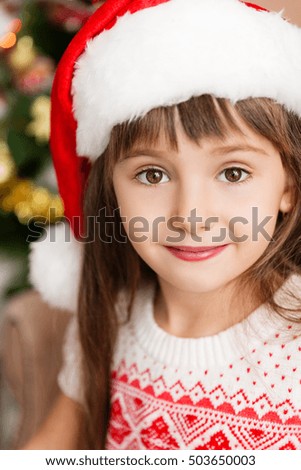 Little girl in Santa hat at home