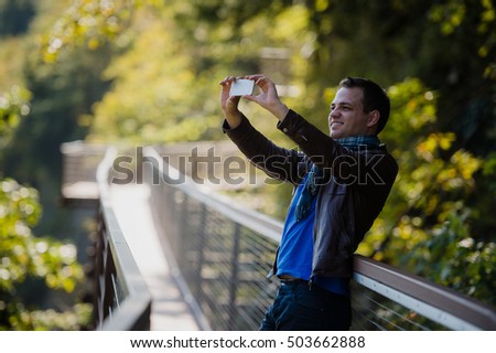 male traveler with smart phone taking a photo of beautiful landscape