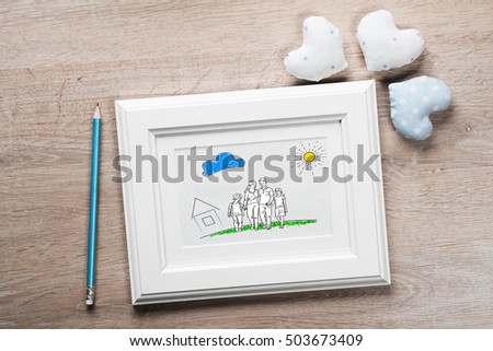 Photo frame with happy family drawing on wooden table
