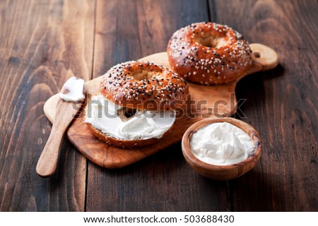 Whole grain bagels with cream cheese on wooden board, selective focus Royalty-Free Stock Photo #503688430