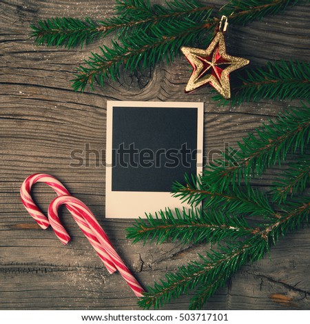 Christmas wooden background with photo frame, red star, candy cane and snow fir tree. Top view with copy space. Holiday concept, Toned