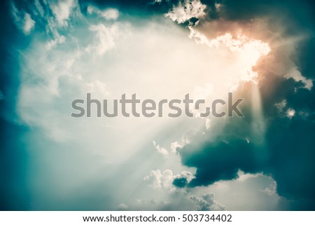 Dramatic Sky and Sun Rays Background. Stormy Clouds in Dark Sky. Sunbeams Light and Moody Cloudscape. Toned and Filtered Photo with Copy Space.