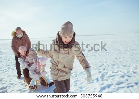 Teen-son rides his family on a sled in a winter