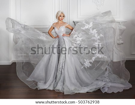 Fashion Bride in gorgeous wedding dress studio portrait, model with bridal makeup and hairstyle in diamond crown, stylish bride in jewelry. Beautiful beauty bride wear lace marriage dress in interior