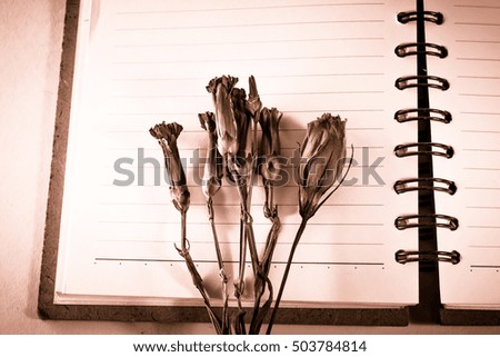 Blank notebook with flower on vintage wooden table
