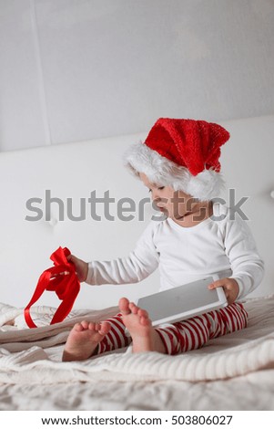 kid in Santa hathat with tablet christmas present light background, New Year's home concept
