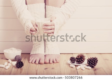 female feet in white socks on the floor with a cup of tea