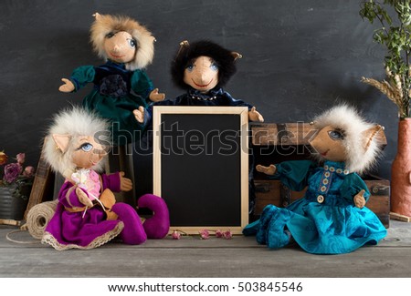 Collection handmade dolls with empty blackboard on the wooden table.
