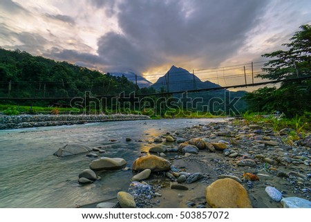Magnificent mountain landscape river,forest and cloudy sky during sunset with mountain Nungkok and the majesty of mountain Kinabalu as background at Tambatuon village,Kota Belud,Sabah,Borneo.
