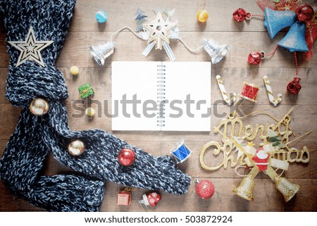 Flat lay of empty notebook, winter scarf and christmas decoration items on wood background, vintage filter