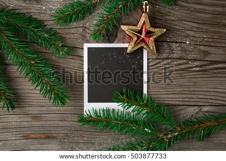 Christmas wooden background with photo frame, red star and snow fir tree. Top view with copy space. Holiday concept