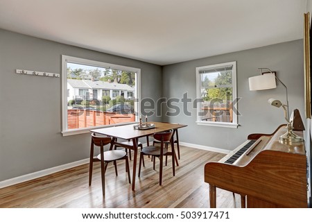 Gray dining room interior with piano and wooden table and four chairs. Northwest, USA