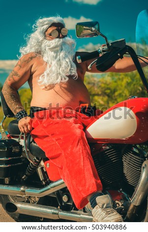 Sunburned Santa biker riding motorcycle on summer vacations