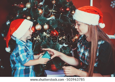 beautiful portrait of happy mother and son on the background of the Christmas tree in new year room with gifts. The idea for postcards. Soft focus. Shallow dof