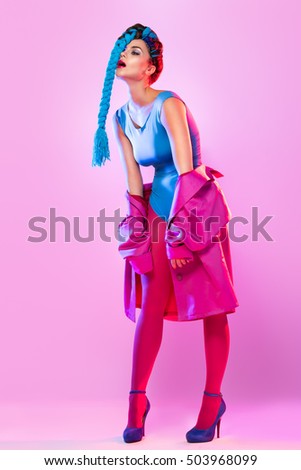 Stylish woman in colorful clothes with threads in her tail over pink background