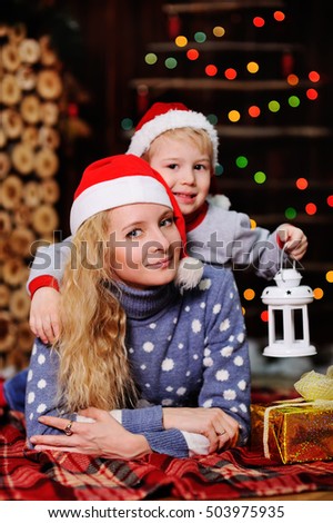 Mother and son in red caps of Santa Claus on a background  Christmas lights