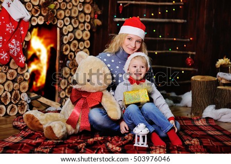 Mother and son in caps of Santa Claus on a background  the cozy fireplace