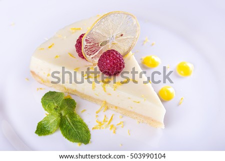 piece French lemon tart, garnished with fresh raspberries, mint and slice of lemon