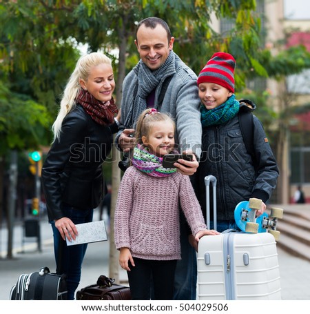 Parents with two kids and baggage taking a selfie on smartphone 