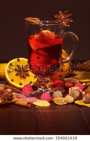 Mulled wine, oranges with cloves and star anise, nuts, raspberries and sweets on a brown background.