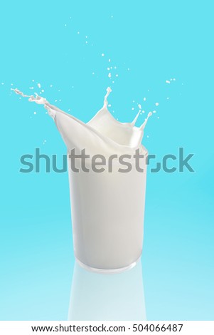 Pouring a glass of milk creating splash on blue background,milk